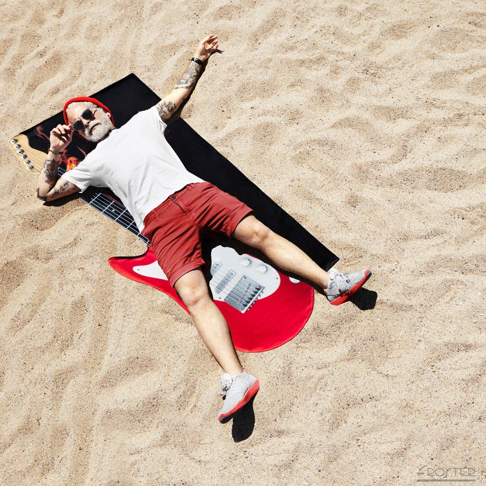 Mężczyzna leży na ręczniku gitarze