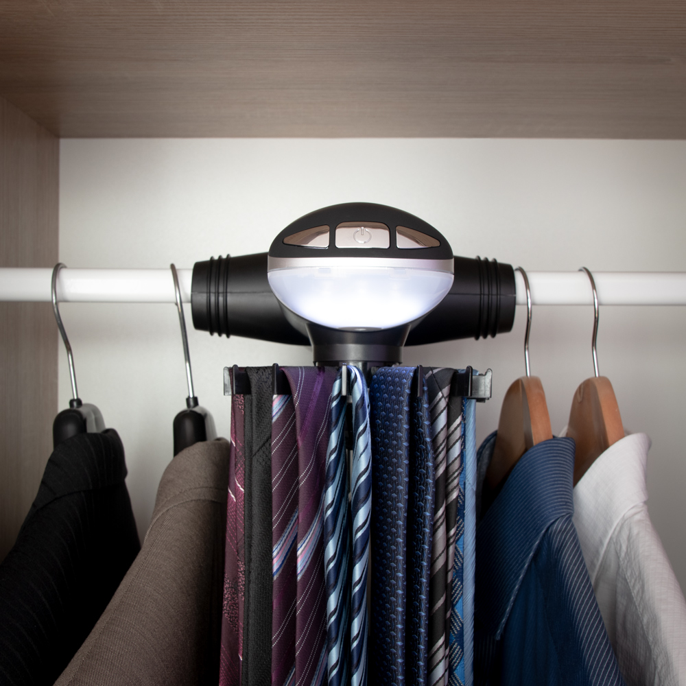 Wnętrze szafy, a w nim elektryczny wieszak na krawaty ze świecącymi diodami LED, na którym wisi kolekcja krawatów.