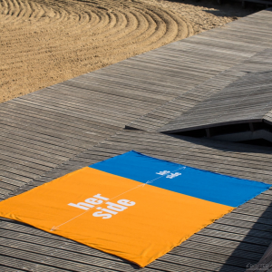 Ręcznik plażowy z napisami her side his side rozłożony na plaży