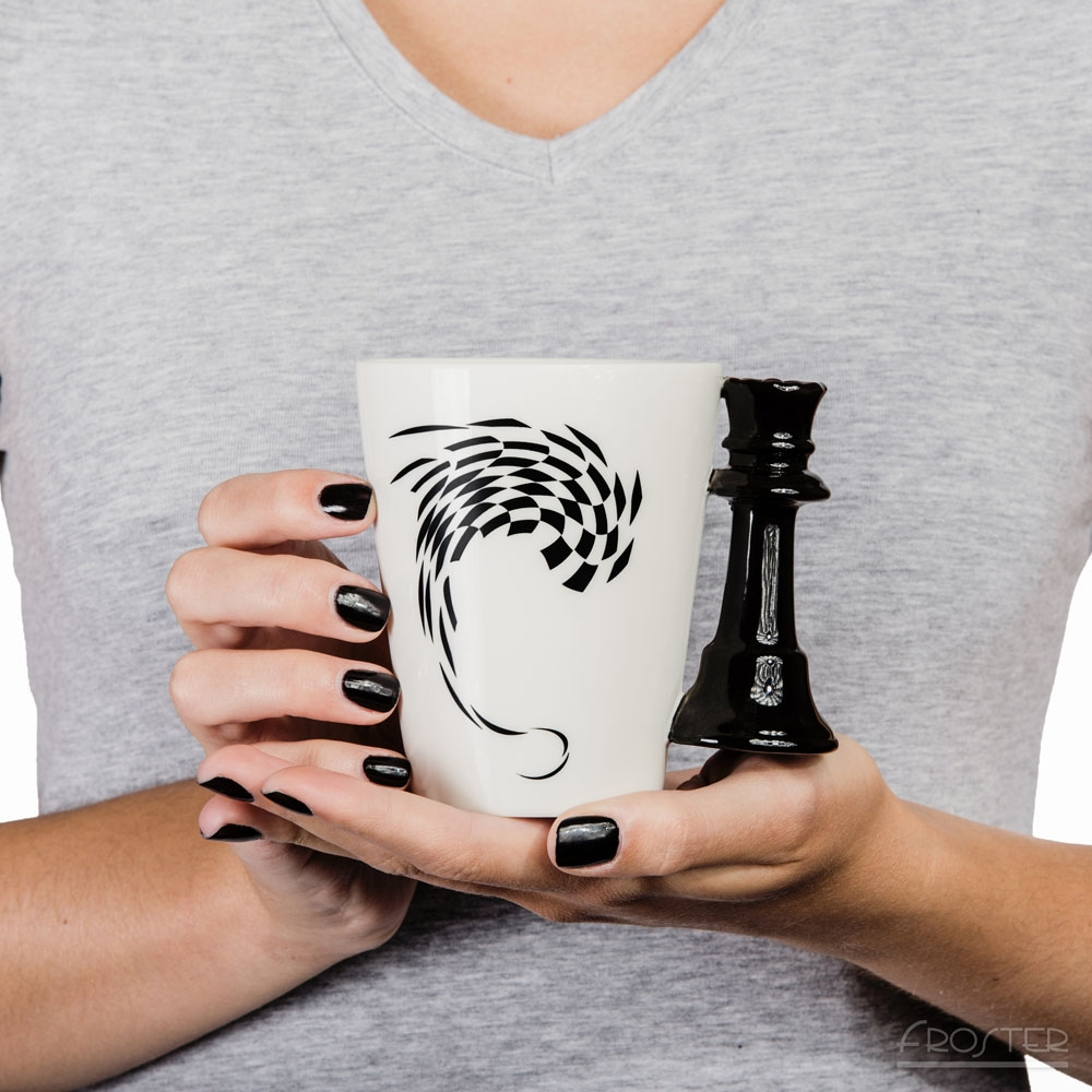 Kobieta trzyma w dłoniach kubek z uchwytem figury szachowej - królowa