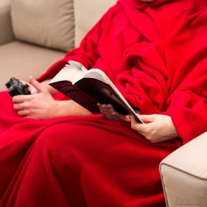 Para w kocu z rękawami dla dwojga, mężczyzna swobodnie gra na konsoli, kobieta czyta książkę