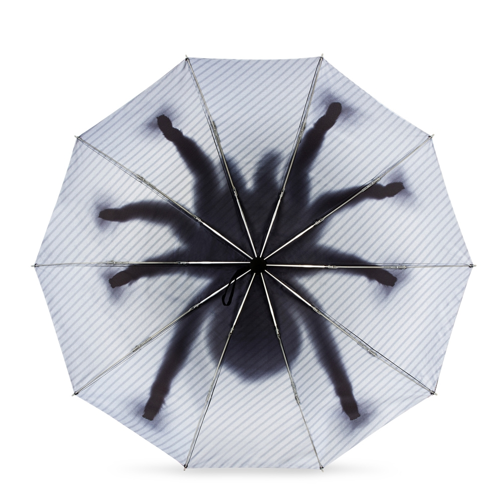 Rozłożony parasol z nadrukiem cienia wielkiego pająka wewnątrz.